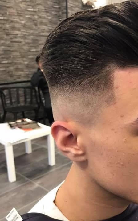 Een afgewerkte fade die overloopt in een naar achteren gekamd kapsel